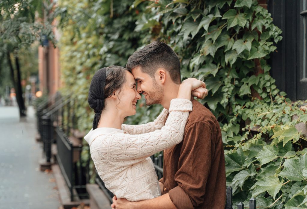 Trennis and Maria kissing in front of climbing greenery